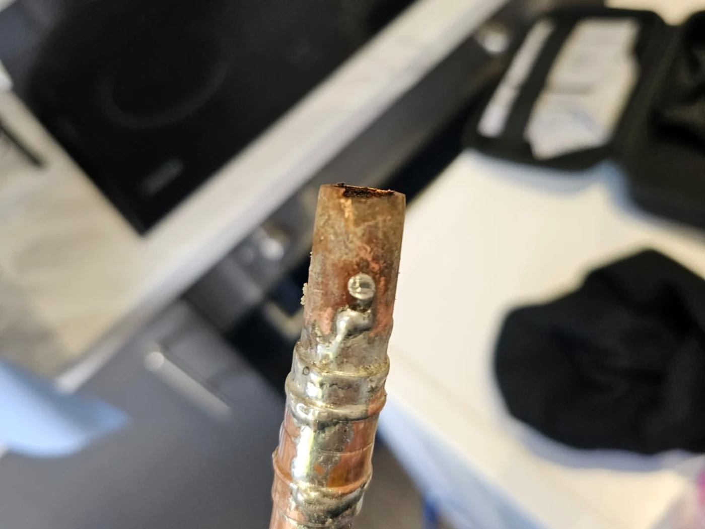 Removed copper pipe section examined during a concealed water-pipe repair