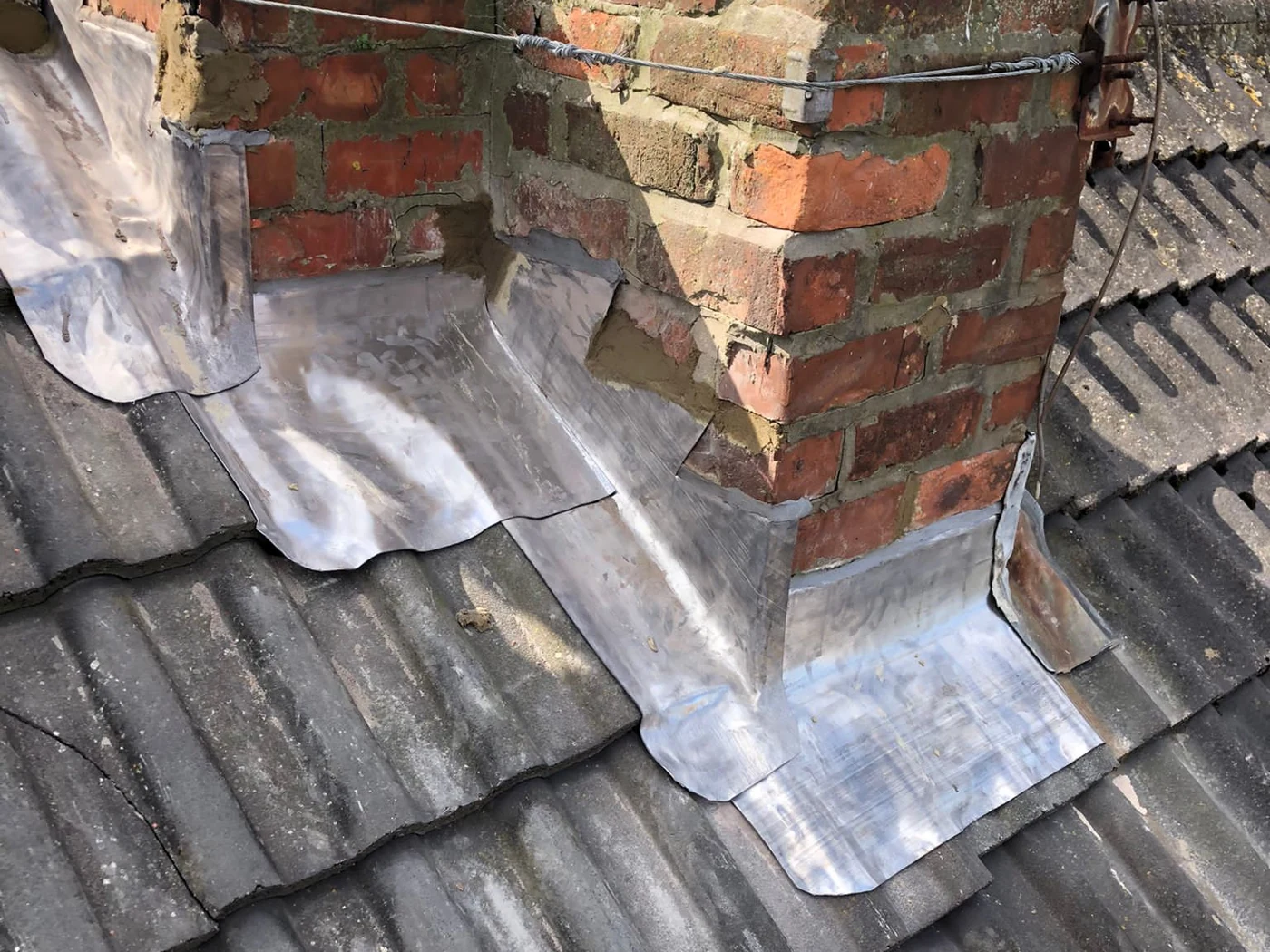 Lead aprons and stepped flashing around a brick chimney on a tiled roof in Blyth