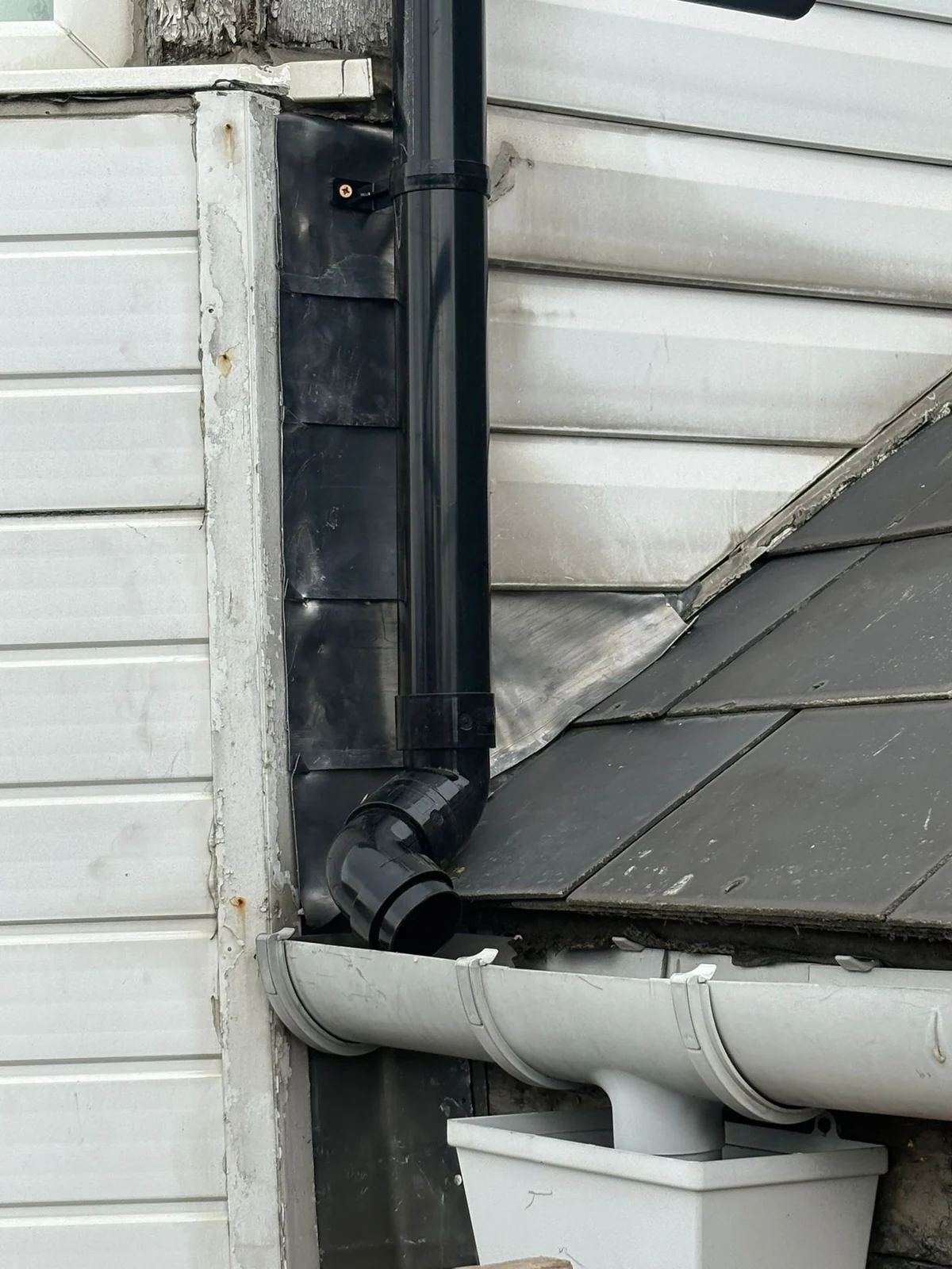 Black rainwater pipe beside grey guttering and lead flashing at the Blyth property