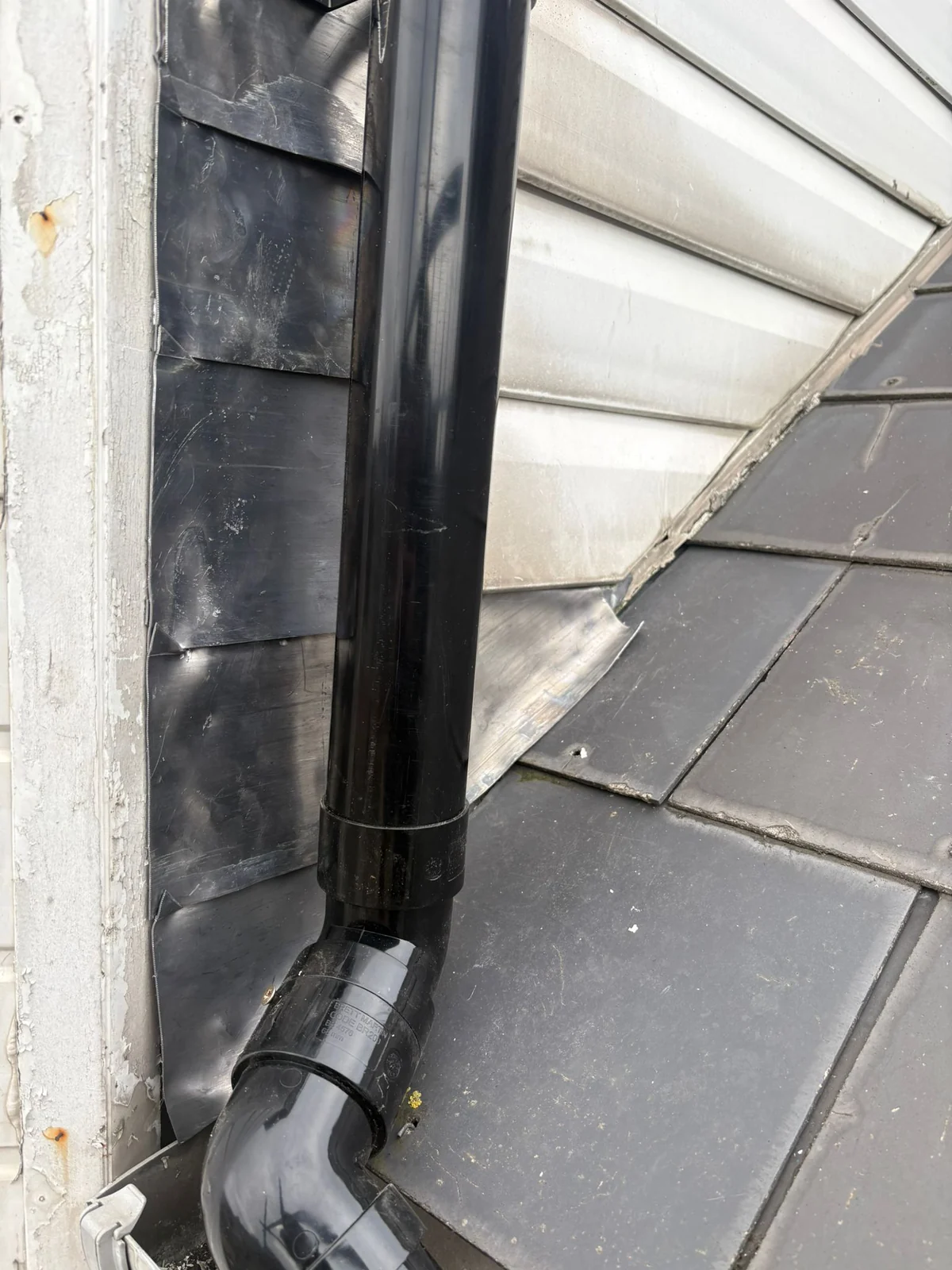 Close view of the black rainwater downpipe connection